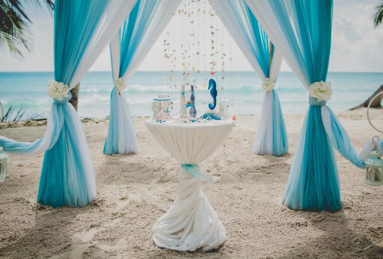 Blue and white wedding aisle in a beach surrounded by palms with the sea on the background